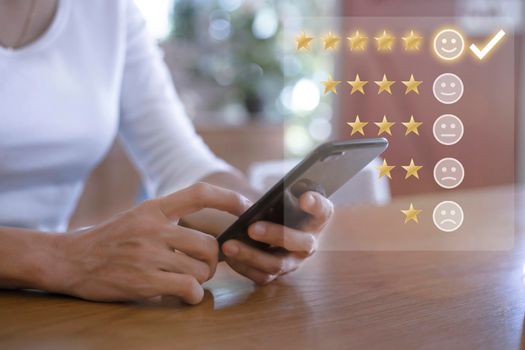 Customer service and Satisfaction concept ,Women hand hold smart phone empty screen choose the 5 star icon to give satisfaction in service. rating very impressed in coffeeshop.
