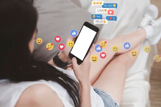 Asian woman sitting on sofa relaxing with cell phone white screen. young woman relax with social media only. women using the smart phone holding and typing with others through emoji and text online.