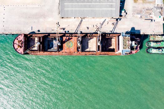 Aerial drone top view of containers cargo ship at industrial import-export port. Business logistic import and export freight transportation by container ship in open sea