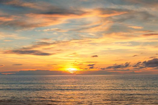 Beautiful sunset over the clam sea with cloud and sky background. Sunset over tropical beach. Nature summer  concept. Peak sunset over sea with yellow light reflect in cloud.