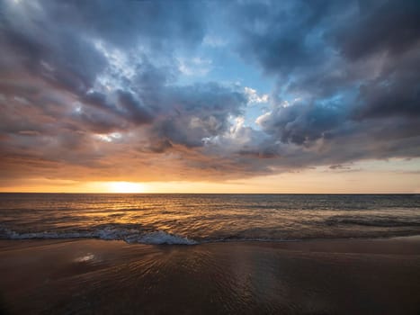 Beautiful sunset over the calm sea with cloud sky background. Sunset over tropical beach. Nature summer  concept. Peak sunset over sea with yellow light reflect on sea water. Tranquil seascape. 