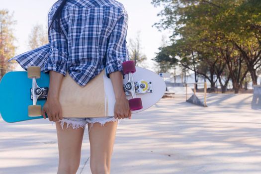Close up on young women hand hold skateboard, surf skate on public skate ramp park background. Free relax skateboard surf skate trendy concept. Fashion portrait of female hands holding surf skateboard