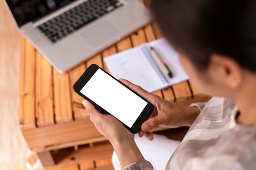 Top view female hands holding smart phone with blank white screen. Women hands workspace, close-up hand holding smartphone blank screen for text and content at cafe coffee shop
