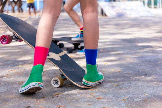 Close-up Asian girl surf skate or skateboard outdoors on beautiful morning. Happy young girl play surf skate at ramp park on morning time. Close up Asian women leg wear sneaker play surf skate on public park. Sport concept
