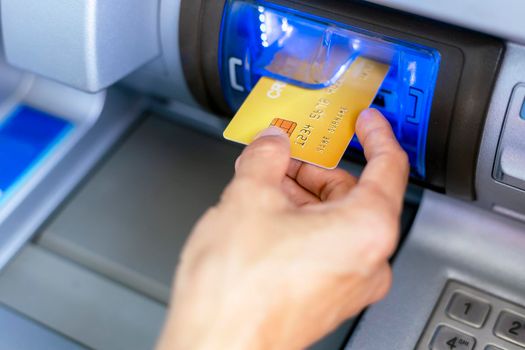 Close up hand of women with a credit card, using an ATM. Women using an atm machine with his credit card. Hand holding credit card insert into ATM card slot