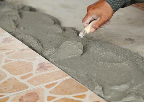 renovation - handyman laying tile, trowel with mortar