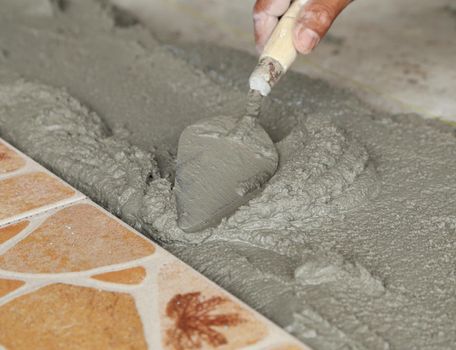 renovation - handyman laying tile, trowel with mortar