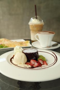 Chocolate Lava Cake with ice cream and beverage in cafe