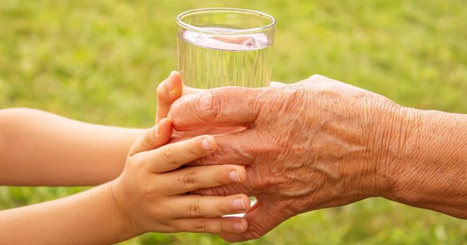 Grandmother giving a glass of clean water to a child. Selective focus. nature.