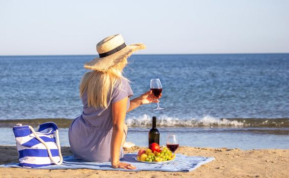 Beautiful smiling woman with a glass of wine on the beach. Fruit red wine. Selective focus.