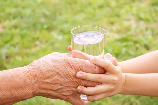 Grandmother giving a glass of clean water to a child. Selective focus. nature.