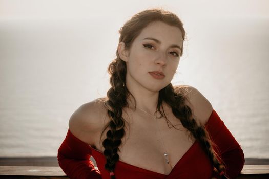 Closeup video portrait of sensual young brunette woman in red dress, happily dancing outdoors isolated on blurry sea background with natural bokeh in soft warm sunset backlight