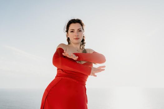 Closeup video portrait of sensual young brunette woman in red dress, happily dancing outdoors isolated on blurry sea background with natural bokeh in soft warm sunset backlight