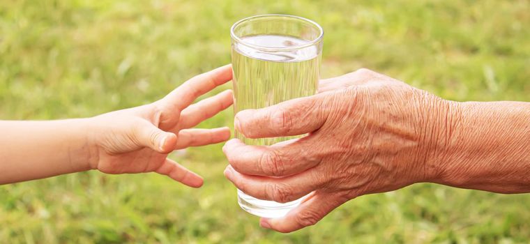 Grandmother giving a glass of clean water to a child. Selective focus. nature.