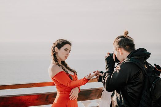 Closeup video portrait of sensual young brunette woman in red dress, happily dancing outdoors isolated on blurry sea background with natural bokeh in soft warm sunset backlight