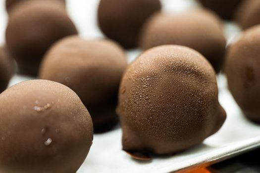 Close-up of chocolate balls with condensate after freezing. Homemade candies with small water drops