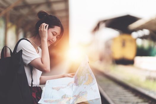 Young traveler woman looking on maps planning trip at train station. Summer and travel lifestyle concept