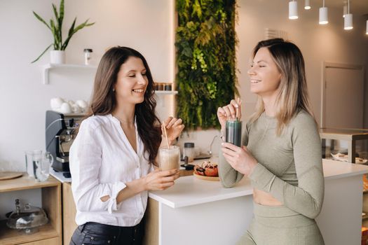 Two sporty-looking girls with cocktails in their hands discuss healthy eating and diet.