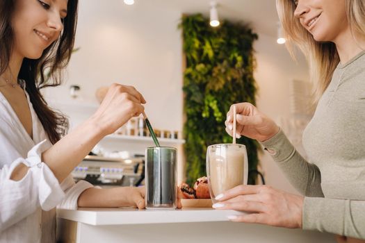 Two sporty-looking girls with cocktails in their hands discuss healthy eating and diet.