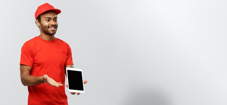 Delivery Concept - Portrait of Handsome African American delivery man or courier showing tablet on you to check the order. Isolated on Grey studio Background. Copy Space