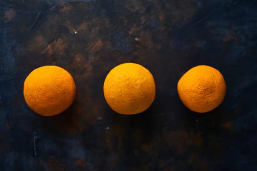 Three oranges on a dark background. Concept. Citrus on the table