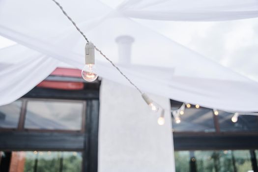 Light bulb decor in an outdoor party. High-quality photo. Wedding decor. Garland of paws.