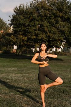 Asian girl does qigong meditation in the green park. Young woman stand in special stance and do special hand movement