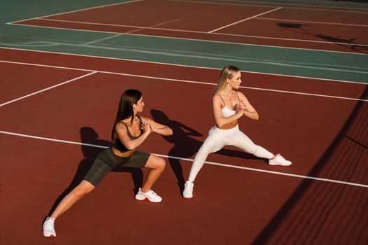 Group stretching of 2 fit girls. Active sport lifestyle. Outdoor training.