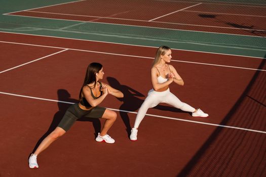 Group stretching of 2 fit girls. Active sport lifestyle. Outdoor training.