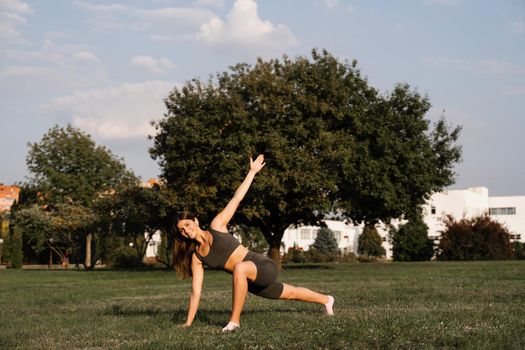 Fit girl training on green grass in the park. Outdoor workout. Sport lifestyle of active young woman