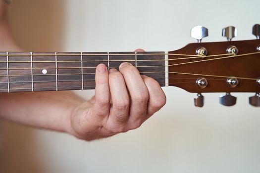 Guitar Player Hand or Musician Hand in Am Minor Chord on Acoustic Guitar String with soft natural light in close up view