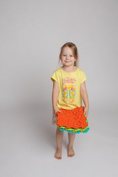 Stock photo of a child playing with colorful bright rubber pads for improving and developing fine motor skills on the floor. She is sitting on her haunches in studio.