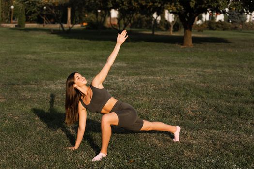 Fit girl does warm-up and stretching exercises in green park. Sports lifestyle