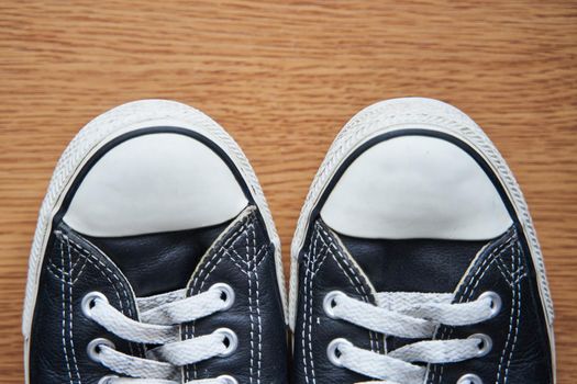 Black leather sneakers on a wooden background. Close-up