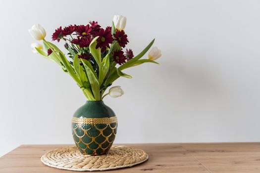 Bouquet of tulips and chrysanthemums in a vase on a white background. High-quality photo