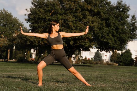 Qigong meditation exercises outdoor. Fit asian girl does chinese training on the green grass in the park