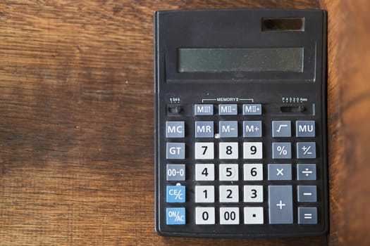 Black calculator on a dark wooden background.