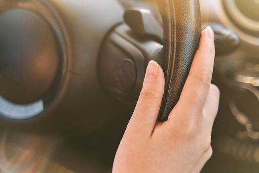 Female hands on the steering wheel of a car while driving. sunset the background, the windshield and road. High quality photo