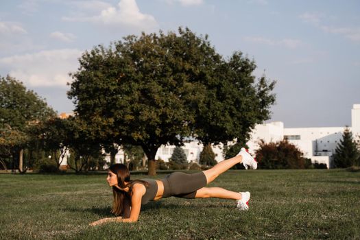 Fit girl does warm-up and stretching exercises in green park. Sports lifestyle