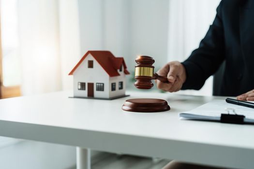 Law, Consultation, Agreement, Contract, Concept Attorney or lawyer focusing on the court hammer is sitting on the chair with a client's complaint to determine the house and land in court.