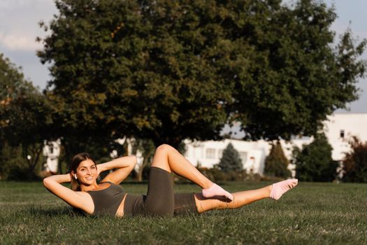 Fit girl training on green grass in the park. Outdoor workout. Sport lifestyle of active young woman