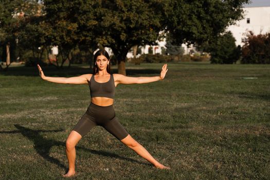 Qigong meditation exercises outdoor. Fit asian girl does chinese training on the green grass in the park