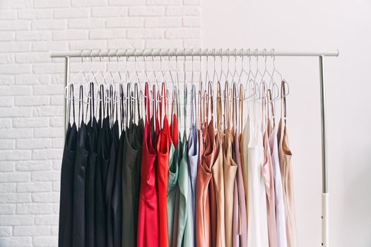 Multi-colored dresses hang on hangers in the store. Sale of women's dresses. Variety of different female colorful clothing hanging.