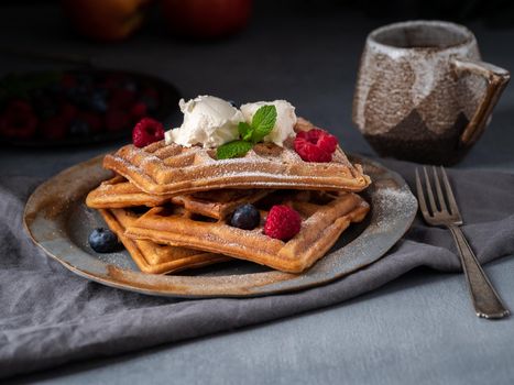 Belgian waffles with raspberries, chocolate syrup. Breakfast with tea on dark background, side view