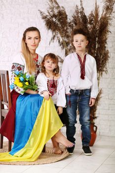 Young woman holds yellow and blue tulips. Ukrainian family. Ukrainian flag. War in Ukraine.