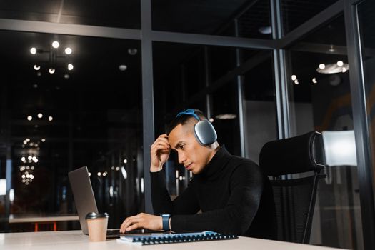 Asian man holding his head and thinking about working online at a laptop. Handsome man worries about remote work