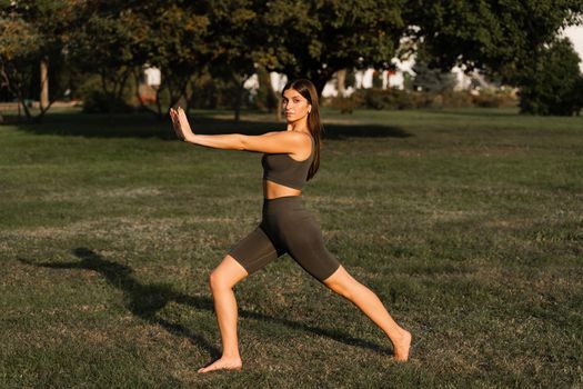 Qigong meditation exercises outdoor. Fit asian girl does chinese training on the green grass in the park