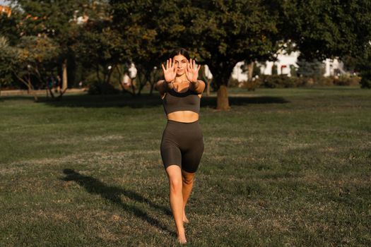 Qigong meditation exercises outdoor. Fit asian girl does chinese training on the green grass in the park