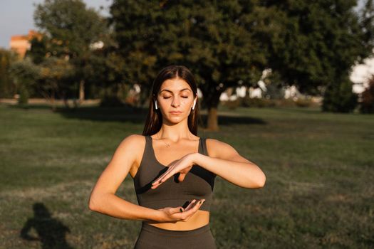 Asian girl does qigong meditation in the green park. Young woman stand in special stance and do special hand movement