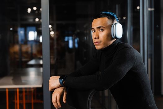 Asian man in headphones working online and listen to music in office. Asian handsome guy with laptop in coworking space